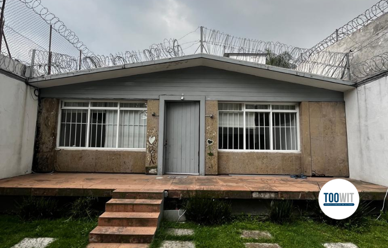 Fachada de una casa de en color café con jardín al frente, ubicada en LAS ARBOLEDAS, LÓPEZ MATEOS, EDOMEX.